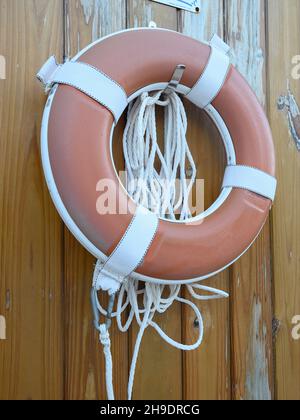 Lifebuoy hängend rote Farbe auf Holz orange Wand. Sicherheitsausrüstung in der Nähe des Pools. Foto 44K aufgenommen bei natürlichem Abendlicht Stockfoto