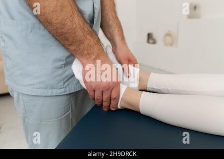 Knieschmerzlinderung in der Klinik. Arzt Physiotherapeut, der heilende Behandlung am Bein des Patienten macht. Therapeut gibt Bein- und Kälbermassage. Osteopathie Stockfoto