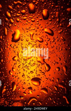Hintergrund. Nahaufnahme. Tropfen auf ein Glas mit einem Orangengetränk. Bier, Tee Stockfoto