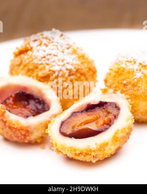 Pflaumenknödel, Pflaumen, Österreich, typisch, süß, Dessert, Gebäck, Krümel, Puderzucker, Obst, Teller, Tisch, weiß, Holz, Holztisch, Quark, gefüllt, du Stockfoto