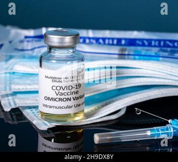 Covid-19 Coronavirus-Impfstoff für Omicron-Variante mit hypodermischer Spritzennadel mit Masken und neuen Spritzen im Hintergrund entwickelt Stockfoto