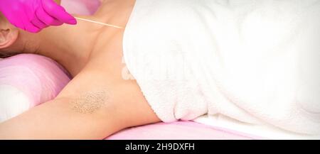 Hand in Handschuh mit Spatel enthaart weibliche Achselhöhlen in einem Spa Stockfoto