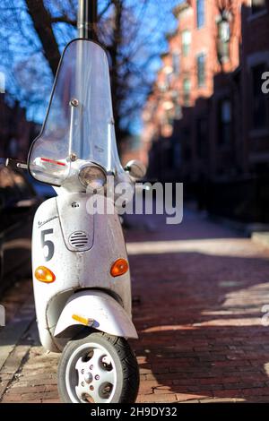 White Vespa Roller geparkt auf gemauerten Bürgersteig in Boston Brownstone Nachbarschaft. Stockfoto