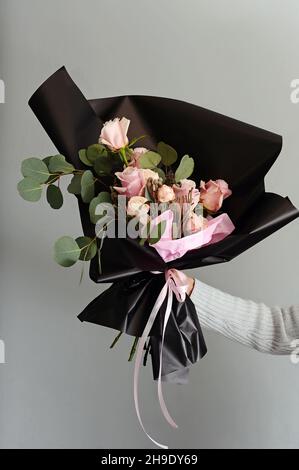 Schönes Geschenk von rosa zarten blühenden Bouquet. Verschiedene frische Blumen und dekorative Pflanzen in schwarzem Papier. Geschenkidee zum Valentinstag. Isoliert Stockfoto