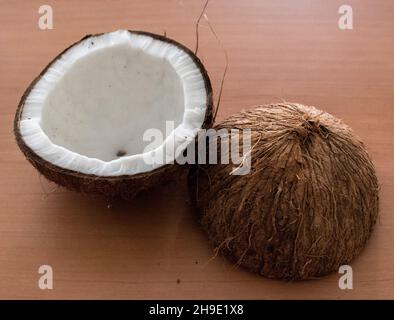 Zwei Hälften einer frischen Kokosnuss auf einer braunen Holzoberfläche Stockfoto