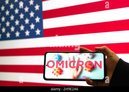Handliches Mobiltelefon mit omicron COVID 19 Variant Strain vor der Flagge der USA mit Nachrichten-App-Benachrichtigung Stockfoto