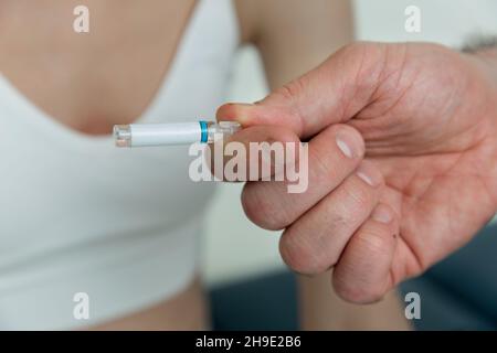 Der Arzt hält kleine Ampullen in den Händen. Nahaufnahme einer kleinen Ampulle mit einem Impfstoff in der Hand des Arztes. Reagenzglas für Allergietest halten. Allergietests Stockfoto