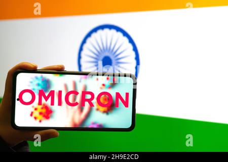 Handliches Mobiltelefon mit omicron COVID 19-Variantenstamm vor der indischen Flagge, die Nachrichten-App-Benachrichtigungen anzeigt Stockfoto