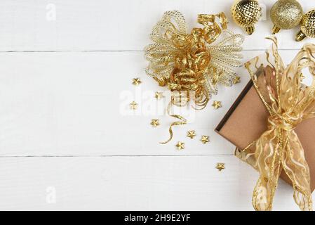 Flaches Weihnachtskonzept. Goldene Geschenke und Ornamente mit Kopierfläche auf rustikalen weißen Brettern. Stockfoto