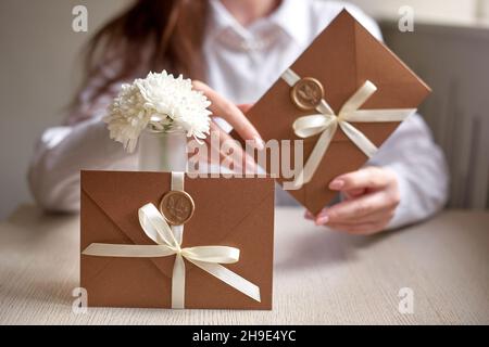 Frau halten versiegelte Umschläge. Einladungsumschlag mit Band und Wachs Siegel, Geschenkgutschein, Hochzeit Einladungskarte Stockfoto