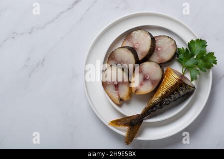 Kopflose Makrele, Stücke Makrele in einem Teller auf einem weißen Tisch. Draufsicht Stockfoto