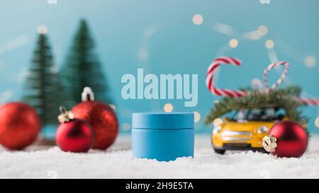 Mockup eines blauen Krug feuchtigkeitsspendende Creme auf Kunstschnee und Weihnachtsspielzeug. Winter Hautpflegekonzept Stockfoto