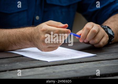 Junge männliche Hände füllen Formulare aus. Junger Mann schreibt. Stockfoto