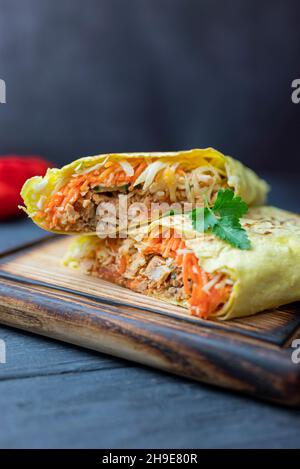 Köstliches Fast-Food-Shawarma in Pita-Brot mit Gemüse und Schweinefleisch und Kalb auf einem Holzbrett Stockfoto