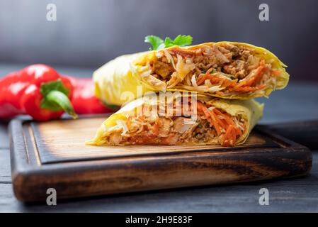 Köstliches Fast-Food-Shawarma in Pita-Brot mit Gemüse und Schweinefleisch und Kalb auf einem Holzbrett Stockfoto