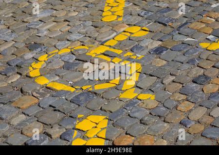 Der Rollstuhl, der ein Symbol für einen Behindertenparkplatz ist, wurde in der Stadt Bern in der Schweiz auf einer gepflasterten Straßenoberfläche gelb gestrichen. Stockfoto