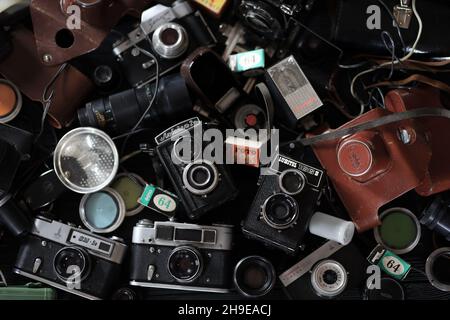 CHARKOV, UKRAINE - 27. APRIL 2021: Filmkameras und eine andere alte Retro-Fotoausrüstung auf schwarzem Holztisch in der Dunkelkammer des Fotografen. Foto Stockfoto