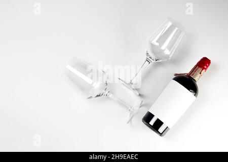 Rotwein-Flasche und Glas auf weißem Hintergrund mit Kopierraum. Flach liegend, Draufsicht Mockup, abstrakte Komposition. Stockfoto