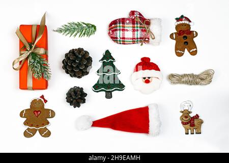 Geschenkbox, Weihnachtsbonbons, Tannenzapfen, dekorative Weihnachtsbaum-Spielzeuge, Weihnachtsmann-Hut und Handschuhe. Flach lag auf weißem Hintergrund. Party Time-Konzept. Stockfoto
