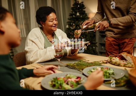 Porträt einer glücklichen afroamerikanischen Großmutter, die beim Weihnachtsessen mit der Familie Essen genießt Stockfoto