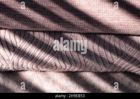 Stapel pastellfarbener Winterpullover auf weißem Hintergrund. Gemütlicher Herbst- und Winterhintergrund. Stockfoto