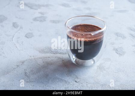 Heißer Kaffee aus doppelwandigen Glas auf grauem, betontem Hintergrund Stockfoto