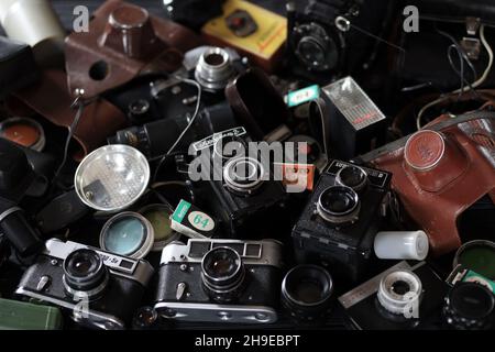 CHARKOV, UKRAINE - 27. APRIL 2021: Filmkameras und eine andere alte Retro-Fotoausrüstung auf schwarzem Holztisch in der Dunkelkammer des Fotografen. Foto Stockfoto