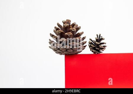 Red Cube Podium mit Kiefernkegel auf weißem Hintergrund. Minimale Weihnachtsfesttagskomposition mit Kopierplatz. Stockfoto