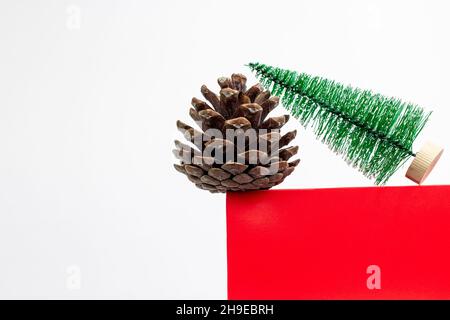 Feuerkegel und kleiner Weihnachtsbaum auf einem roten würfelförmigen Podium. Minimale Weihnachtsfesttagskomposition mit Kopierplatz Stockfoto