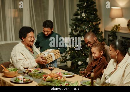 Porträt einer glücklichen afroamerikanischen Großmutter, die das Geschenk eröffnet, während sie Weihnachten mit der Familie genießt Stockfoto