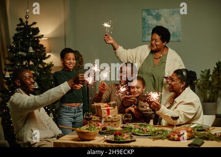 Porträt einer afroamerikanischen Familie, die Wunderkerzen beleuchtet, während sie Weihnachten zu Hause gemeinsam genießt Stockfoto