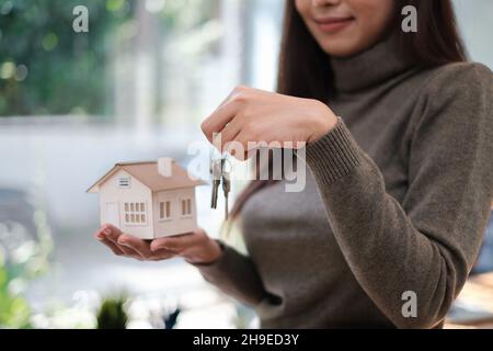 Ein Immobilienmakler demonstriert das Haus-Modell für Kunden, die sich für den Kauf einer Hausversicherung interessieren. Das Konzept der Hausversicherung und Immobilien. Stockfoto