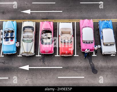 Wie von oben gesehen, steht in Havanna eine Reihe von sechs bunten antiken amerikanischen Autos auf einer Straße, die auf zahlende Passagiere wartet. Stockfoto