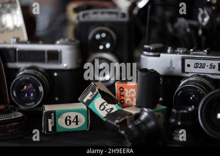 CHARKOV, UKRAINE - 27. APRIL 2021: Filmkameras und eine andere alte Retro-Fotoausrüstung auf schwarzem Holztisch in der Dunkelkammer des Fotografen. Foto Stockfoto