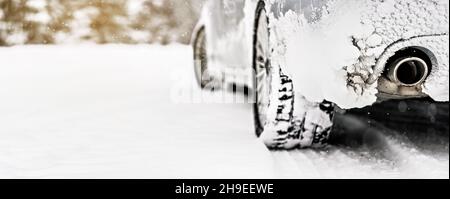 Silbernes Auto bedeckt mit Eis geparkt auf schneebedeckten Straße, Detailansicht von hinten zu Auspuff, verschwommene Bäume Hintergrund leerer Platz für Text links Stockfoto