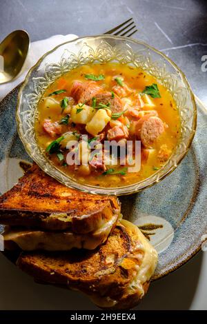 Schinken- und Bohnensuppe mit Kielbasa-Wurst und gegrillten Käse-Sandwiches von gouda Stockfoto