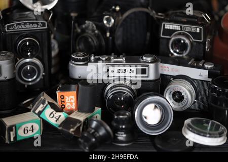 CHARKOV, UKRAINE - 27. APRIL 2021: Filmkameras und eine andere alte Retro-Fotoausrüstung auf schwarzem Holztisch in der Dunkelkammer des Fotografen. Foto Stockfoto