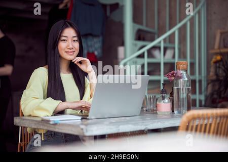 Porträt einer jungen Frau, die glücklich im Café arbeitet Stockfoto