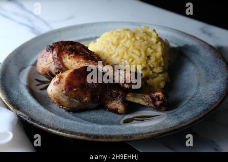 Peruanisches Abendessen pollo a la brasa Hähnchenschenkel mit Aji Amarillo Reis Risotto Stockfoto