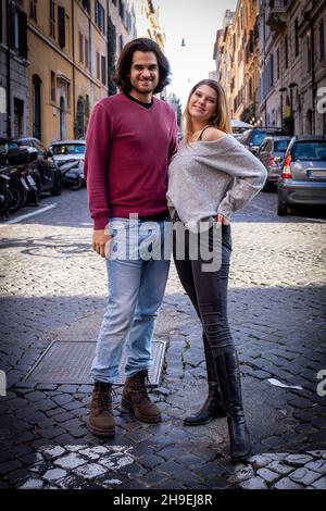 Schönes Paar, das nach Rom reist. Ein junges Paar posiert für ein Foto in den Straßen des historischen Zentrums der Stadt. Im Hintergrund Gebäude an Stockfoto