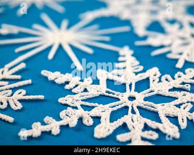 Zarte und sehr real aussehende Häkelschneeflocken, selektiver Fokus. Winterdekoration. Handgemachte Weihnachtsbaum Ornament oder Wanddekor Stockfoto