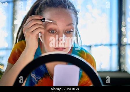 Frau Bloggerin mit Ringlicht während Online-Streaming über die Anwendung Augenbrauenlack. Stockfoto