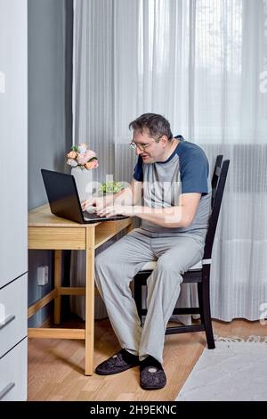 Presbyopie ist eine altersbedingte Sehbehinderung, ein 52-jähriger Mann, der versucht, Text auf dem Laptop-Bildschirm zu lesen. Stockfoto