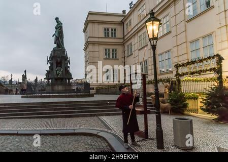 Prag, Tschechische Republik. 06th Dez 2021. Ein Feuerzeug mit einer traditionellen Uniform in Rot und Schwarz leuchtet eine Gaslampe auf der berühmten Karlsbrücke im Zentrum von Prag. Während der Adventszeit werden Gaslampen von lamplighter anstelle einer automatisierten Anlage, die das restliche Jahr über im Einsatz ist, beleuchtet. Die Straßenbeleuchtung in Prag geht auf das Jahr 1847 zurück. Gaslampen wurden bis 1985 verwendet. Im Jahr 2002 wurden Gaslampen im Stadtzentrum wieder eingeführt. Kredit: SOPA Images Limited/Alamy Live Nachrichten Stockfoto