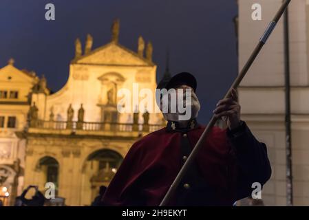 Prag, Tschechische Republik. 06th Dez 2021. Ein Feuerzeug mit einer traditionellen Uniform in Rot und Schwarz leuchtet eine Gaslampe auf der berühmten Karlsbrücke im Zentrum von Prag. Während der Adventszeit werden Gaslampen von lamplighter anstelle einer automatisierten Anlage, die das restliche Jahr über im Einsatz ist, beleuchtet. Die Straßenbeleuchtung in Prag geht auf das Jahr 1847 zurück. Gaslampen wurden bis 1985 verwendet. Im Jahr 2002 wurden Gaslampen im Stadtzentrum wieder eingeführt. (Foto von Tomas Tkacik/SOPA Images/Sipa USA) Quelle: SIPA USA/Alamy Live News Stockfoto