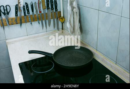 Der Prozess des Kochens von Rühreiern mit Schmalz und Wurst. Der Mann bereitet zwei Portionen vor. Bratpfanne auf dem Elektroherd. Stockfoto