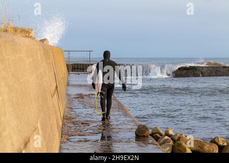 LOSSIEMOUTH, MORAY, SCHOTTLAND - 6. DEZEMBER 2021: Dies ist ein Mann, der am 6. Dece in Lossiemouth, Moray, Schottland, zu den East Beach Waves zum Surfen aufbrechen wird Stockfoto