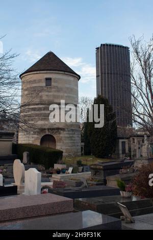 Die Windmühle ohne Segel auf dem Friedhof Montparnasse, mit der Tour Montparnasse im Hintergrund Paris France Stockfoto