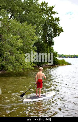 Teenager mit rotem Badeanzug paddeln auf seinem Paddleboard am Clitherall Lake. Clitherall Minnesota, USA Stockfoto