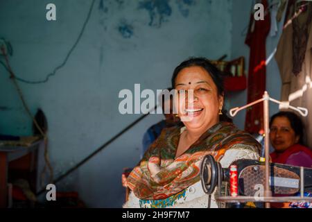 Freundlichen lokalen indischen Schneider arbeiten bei einer traditionellen Nähmaschine, Pragpur, ein Kulturerbedorf im Kagra Bezirk, Himachal Pradesh, Indien Stockfoto